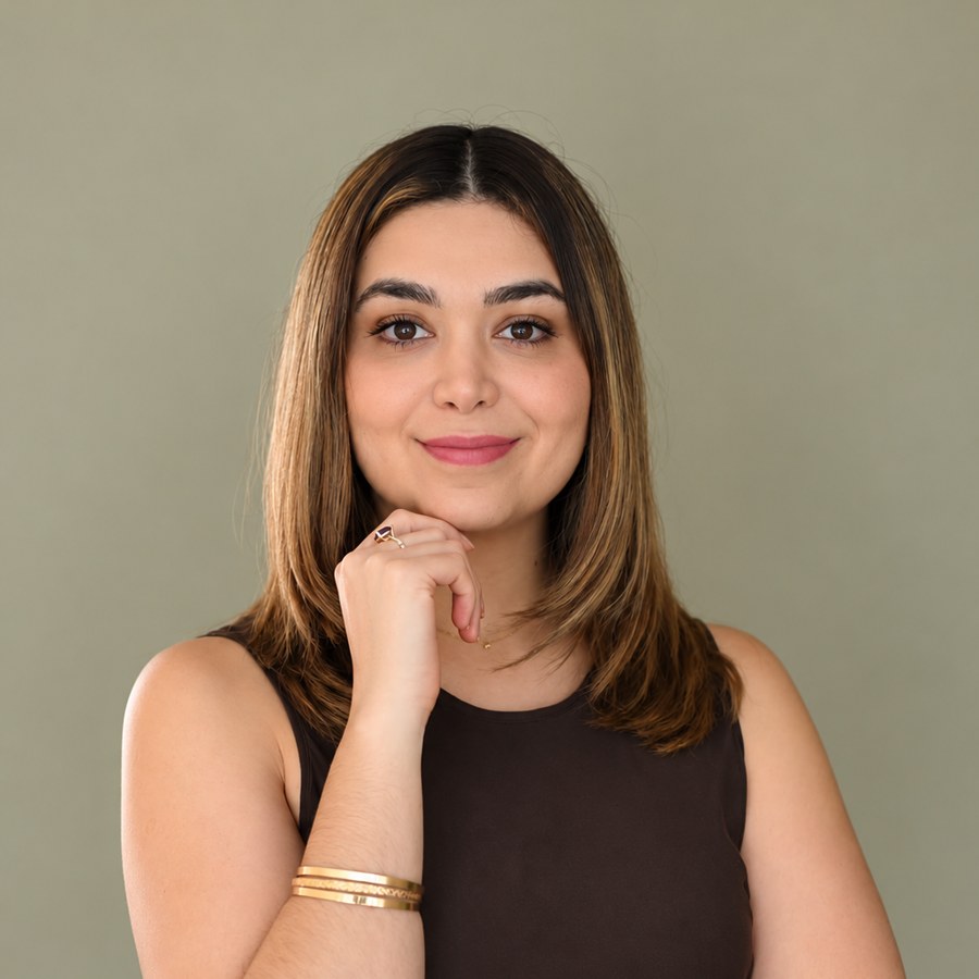 Psicóloga Nancy Mayorga con la mano en el mentón sobre fondo verde